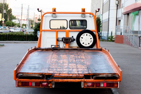 Old wrecker truck with a lot of rusty elements, at city street in summer day