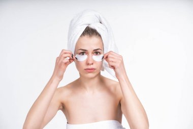 young white girl peels off patches for eyes. Upset. Facial, skin care. Beauty treatments