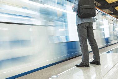 Metro istasyonunda treni bekleyen takım elbiseli adam. Tren hızla geçiyor. Trenin bulanık hareketi. Boş metro istasyonu.