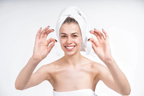 young naked girl in a towel shows patches for the eyes. Laughs happily. Happy Portrait on a blank background. Facial treatment. Skin care.