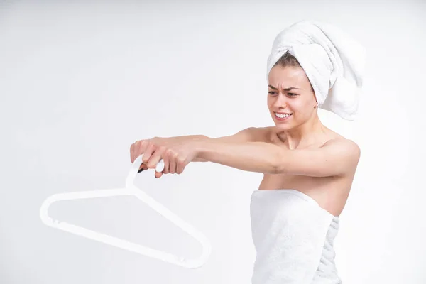 Bela menina nua em uma toalha segurando um cabide para roupas. Em um fundo vazio . — Fotografia de Stock