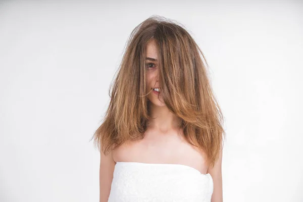 young nude girl in a towel with disheveled hair looks into the camera.