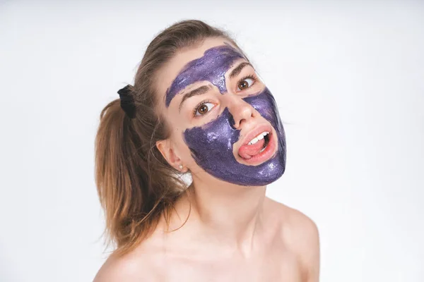 Potret emosional seorang gadis muda european indah dengan topeng kosmetik ungu di wajahnya. Eropa, 22 tahun, putih, latar belakang kosong — Stok Foto