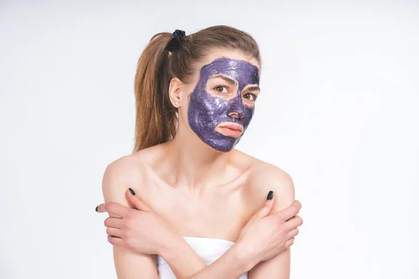 Topeng kosmetik ungu di wajah seorang gadis muda yang cantik, rencana menengah dengan tangan. Tanpa kosmetik, tampilan alami pada latar belakang kosong — Stok Foto
