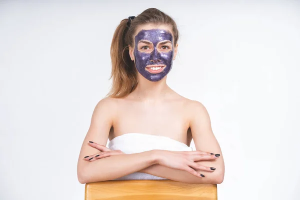 Violet cosmetic mask on the face of a beautiful young girl with a tail hair, medium plan with her hands. Emotional portrait. Without cosmetics, natural look on an empty background — Stock Photo, Image