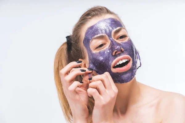 Giovane ragazza con bel viso rimuove una maschera cosmetica viola. Primo piano. Macro. Bianco bei denti — Foto Stock