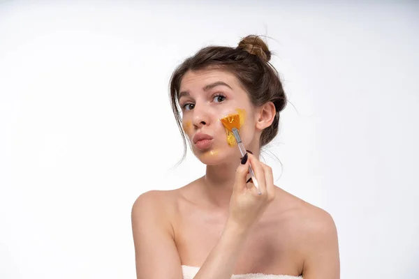 a young girl puts on a face mask for the first time in her life. Can not. Bad skin of the face. Acne on the face. Natural, no makeup. European 25 years old, white