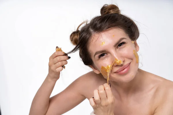 Seorang gadis muda, 25 tahun, melepas topeng kosmetik dari wajahnya. Warna emas. Tangan di frame. Potret emosional besar. Buang air mata dari penutupnya. Suasana hati berbeda . — Stok Foto