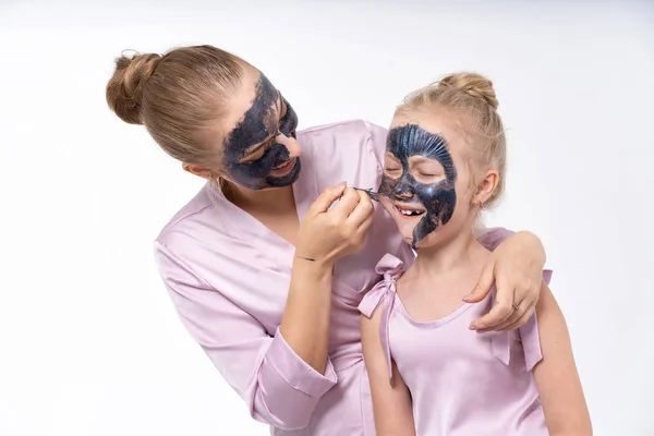 Mladé matky a mladá dcera Evropané provádějí procedury péče o pleť obličeje. Rodinné léčby. Kosmetická péče o pleť. — Stock fotografie