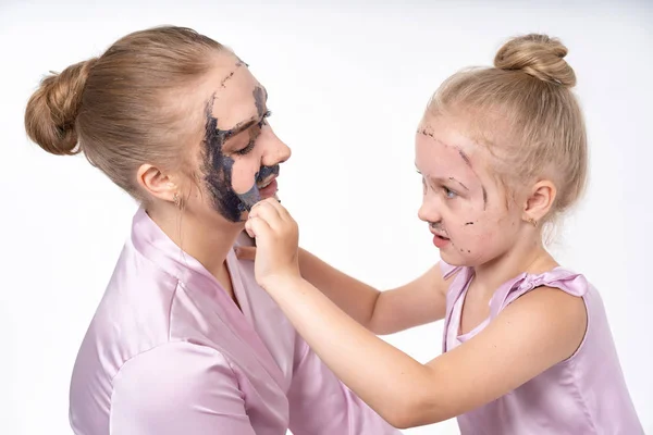 young mothers and young daughter Europeans conduct facial skin care procedures. Family treatments. Cosmetic skin care.