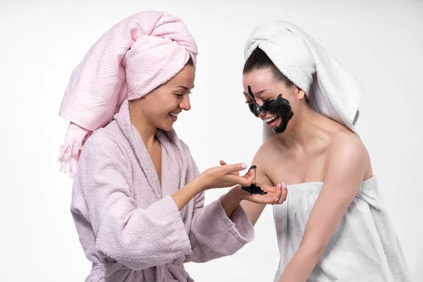 Fidanzate si aiutano a vicenda mettere sul viso una maschera cosmetica, divertirsi e indulgere nel processo. Le ragazze si prendono cura l'una dell'altra e si divertono . — Foto Stock