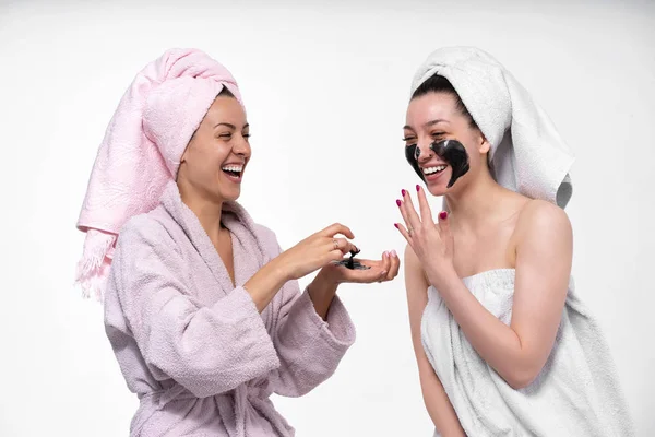 girlfriends help each other put on face a cosmetic mask, having fun and indulge in the process. Girls care about each other and have a great time.