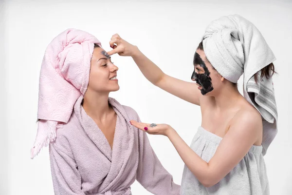 sisters help each other in facials, apply a cosmetic mask, communicate, hug and have fun in the process. They love each other.
