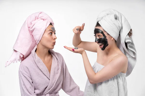 Copines s'aident mutuellement mettre sur le visage un masque cosmétique, s'amuser et se livrer au processus. Les filles se soucient les unes des autres et passent un bon moment . — Photo