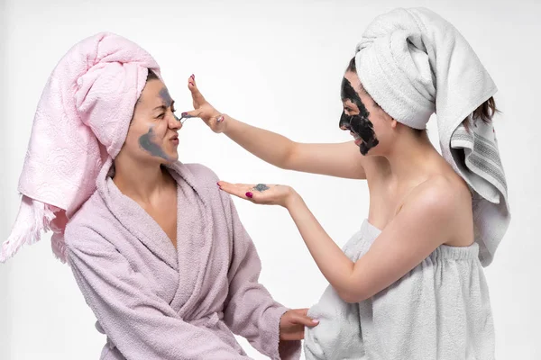 Copines s'aident mutuellement mettre sur le visage un masque cosmétique, s'amuser et se livrer au processus. Les filles se soucient les unes des autres et passent un bon moment . — Photo