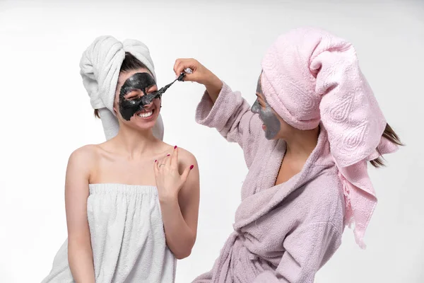 Hermanas ayudan a los demás a eliminar las máscaras faciales de la cara para curar la piel. Tener un gran tiempo juntos y divertirse . — Foto de Stock