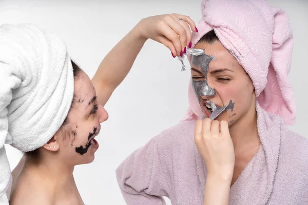 Gli amici vicini insieme sono impegnati in procedure cosmetiche per ringiovanimento facciale. Divertiti e divertiti. Mostra sentimenti gli uni per gli altri . — Foto Stock