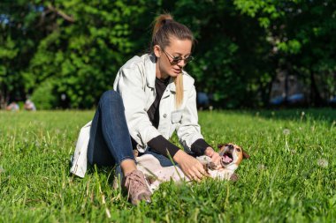 Genç bir kız parkta köpek Jack Russell Terrier 'la oynuyor.