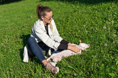 Genç bir kız parkta köpek Jack Russell Terrier 'la oynuyor.