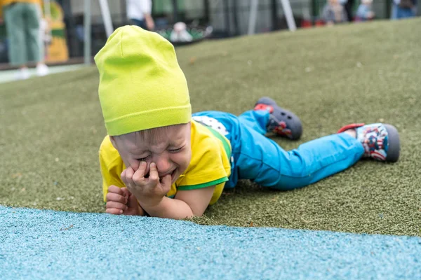 2歳の小さな男の子が落ちて、彼の顔を殴り、泣いて、傷ついた — ストック写真