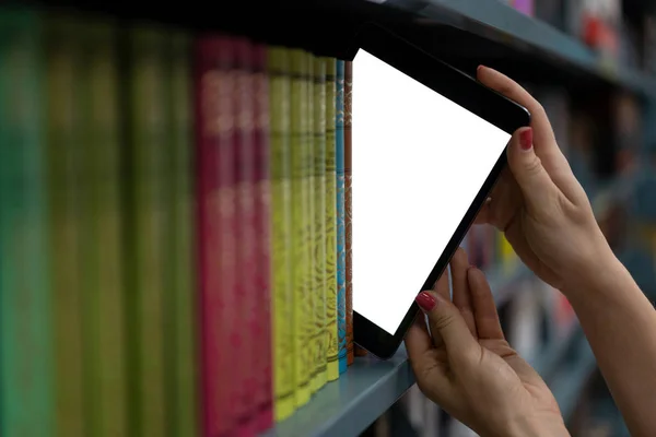 Dziewczyna wyciąga komputer typu tablet z półki na książki. cyfrowy temat świata — Zdjęcie stockowe