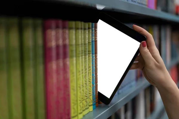 Дівчина витягує планшетний комп'ютер з полиці для книг. тема цифрового світу — стокове фото