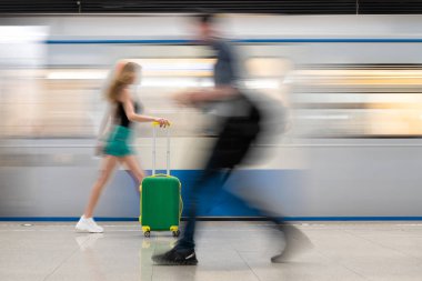 yeşil bir bavul ile kız Metro İstasyonu, tren istasyonunda hareketli bir tren boyunca gider. Çok güzel bulanık hareket. Ana rakam bir bavul olduğunu.