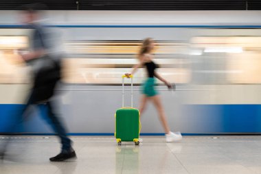 yeşil bir bavul ile kız Metro İstasyonu, tren istasyonunda hareketli bir tren boyunca gider. Çok güzel bulanık hareket. Ana rakam bir bavul olduğunu.