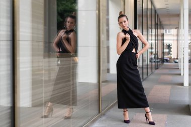 Avrupa modeli aslında butik yakınında siyah bir elbise içinde poz. Camın içinde yansımasını görebilirsiniz. Reklam moda trendleri için çok şık ilginç bir atmosfer.