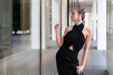 Güzel bir Avrupa modeli bir dükkan penceresi yakınında siyah bir elbise içinde poz olduğunu. Yansımasını görebilirsiniz. Reklam moda trendleri için şık bir atmosfer. Ortalama plan