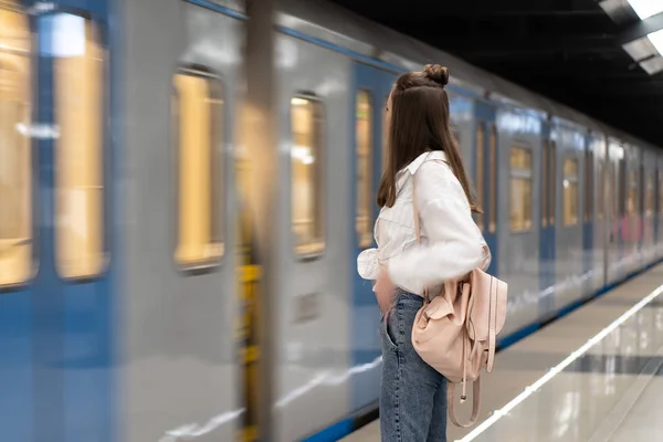 Uzun saçlı genç beyaz kız. Sırt çantasıyla. Metro istasyonunda dikilip treni bekliyorduk. Hareket gerçekliğinin etkilerini aktarmak için tren odak dışı..