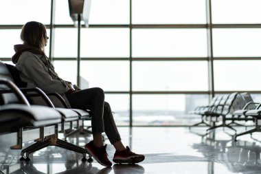 Avrupalı genç bir kız kalkış için bekleme alanında havaalanında oturuyor. Ve yaklaşan geziyi düşünüyorum..