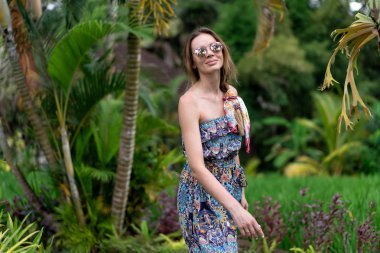 Güzel kız yeşil bir parkta yürüyor yaz güneşli havalarda ve hayatın tadını çıkarıyor..