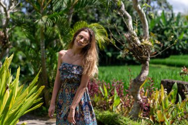 Güzel kız yeşil bir parkta yürüyor yaz güneşli havalarda ve hayatın tadını çıkarıyor..