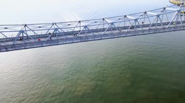 İnsanlar köprüden geçerken Florianopolis, Santa Catarina, Brezilya 'daki Hercilio Luz Köprüsü' nün altından geçen bir teknenin hava görüntüsü.