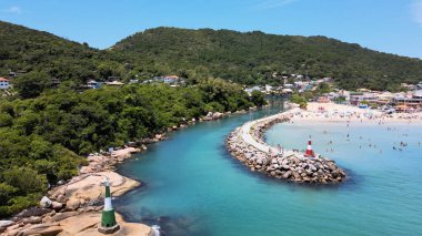 Florianpolis, Santa Catarina, Brezilya 'ya tekne girişi ve çıkışı için küçük bir deniz feneri bulunan Barra da Lagoa plaj kanalı iskelesinin havadan görüntüsü.