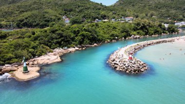 Florianpolis, Santa Catarina, Brezilya 'ya tekne girişi ve çıkışı için küçük bir deniz feneri bulunan Barra da Lagoa plaj kanalı iskelesinin havadan görüntüsü.