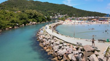 Florianpolis, Santa Catarina, Brezilya 'ya tekne girişi ve çıkışı için küçük bir deniz feneri bulunan Barra da Lagoa plaj kanalı iskelesinin havadan görüntüsü.