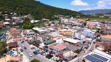 Florianpolis, Santa Catarina, Brezilya 'daki Barra da Lagoa plajının havadan görünüşü güneşli bir yaz gününde kum üzerinde şemsiyeler, kalabalık barlar ve deniz dalışı yapan insanlarla doludur..