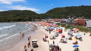 Florianpolis, Santa Catarina, Brezilya - Barra da Lagoa Sahili 'nin havadan görünüşü, güneşli bir günde insanlarla ve şemsiyelerle dolu.