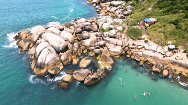 Florianpolis, Santa Catarina 'daki Barra da Lagoa' daki doğal havuz manzarası. Dağ yamacındaki büyük kayalar turkuaz ve zümrüt yeşili okyanusla birleşiyor.