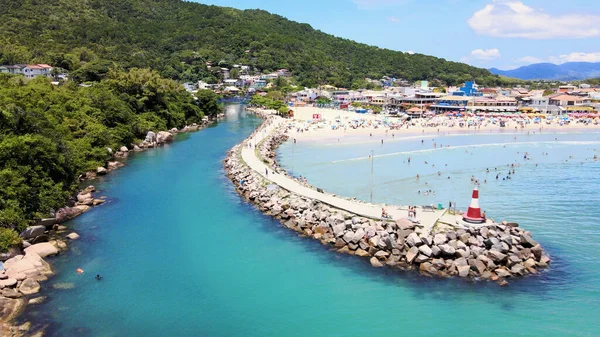 Florianpolis, Santa Catarina, Brezilya 'ya tekne girişi ve çıkışı için küçük bir deniz feneri bulunan Barra da Lagoa plaj kanalı iskelesinin havadan görüntüsü.
