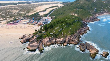 Joaquina Sahili, Atlantik Ormanı ve turkuaz okyanusla kaplı kayalık kıyı şeridini Florianopolis, Santa Catarina, Brezilya 'da ufukta birçok dağ ve kum tepesi görüyordu..