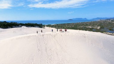 Florianpolis, Santa Catarina 'daki Joaquina Sahili' nin hava manzarası. İnsanlar kumda, kumsalda, sporda, kum tepeciklerinde, bitki örtüsünde, ekolojik ve turistik göllerde sörf yapıyor..