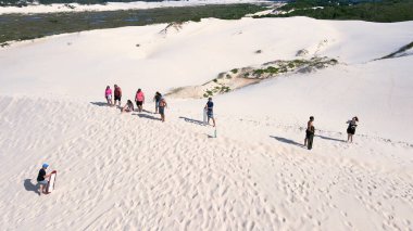 Florianpolis, Santa Catarina 'daki Joaquina Sahili' nin hava manzarası. İnsanlar kumda, kumsalda, sporda, kum tepeciklerinde, bitki örtüsünde, ekolojik ve turistik göllerde sörf yapıyor..