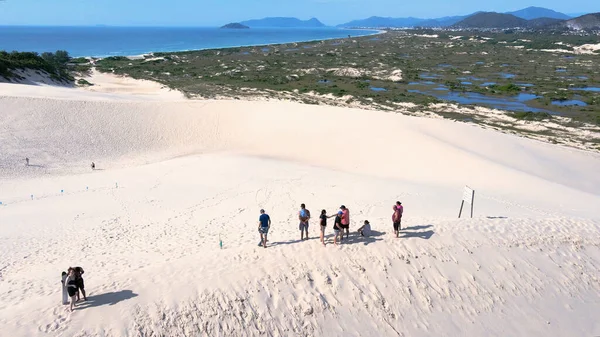 Florianpolis, Santa Catarina 'daki Joaquina Sahili' nin hava manzarası. İnsanlar kumda, kumsalda, sporda, kum tepeciklerinde, bitki örtüsünde, ekolojik ve turistik göllerde sörf yapıyor..