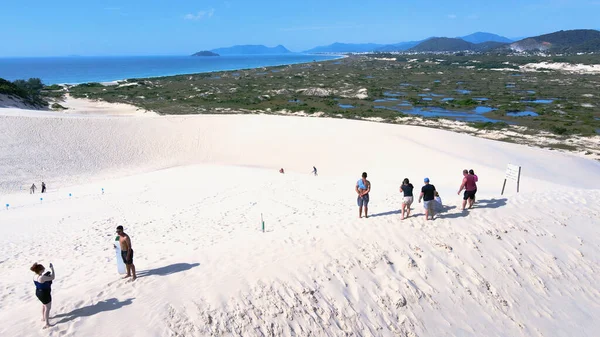 Florianpolis, Santa Catarina 'daki Joaquina Sahili' nin hava manzarası. İnsanlar kumda, kumsalda, sporda, kum tepeciklerinde, bitki örtüsünde, ekolojik ve turistik göllerde sörf yapıyor..