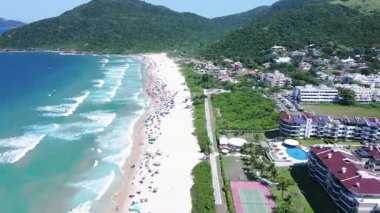 Dağlar ve kentsel alanla çevrili, Florianopolis, Santa Catarina 'da deniz kenarındaki evler ve binalar ile Brava sahilinin havadan görünüşü, yörünge manzarası..