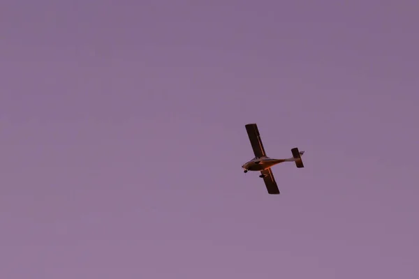 Avião amarelo voando contra um céu rosa — Fotografia de Stock