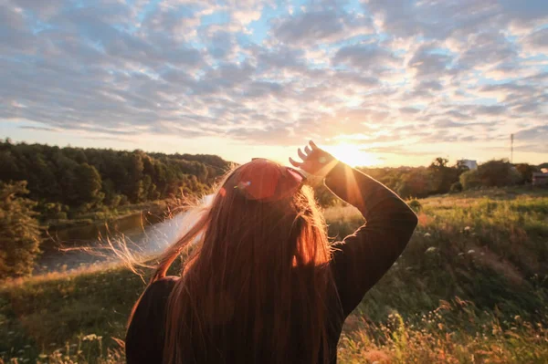 Mujer adulta joven de pie sola y mirando fijamente la puesta de sol amarillo anaranjado sobre el río. — Foto de Stock